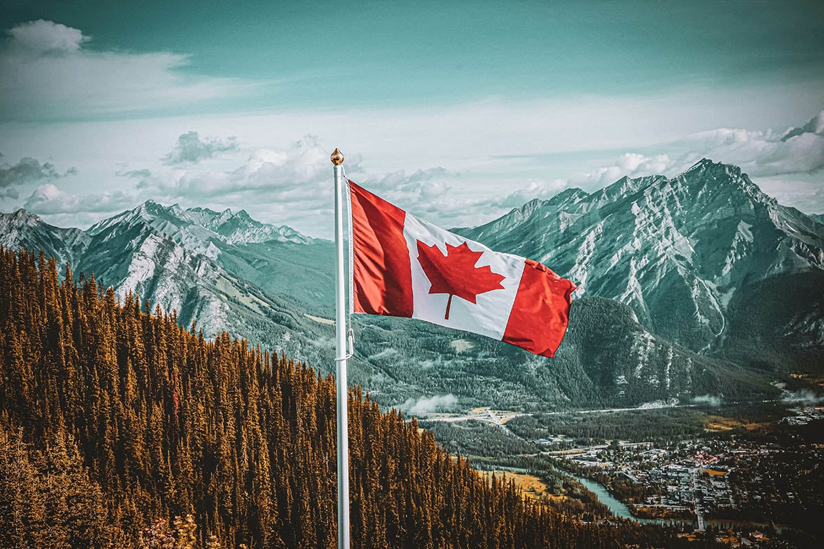 canada flag with wilderness and mountains in the background