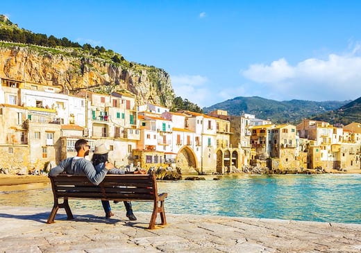 couple sitting on a bench by water in italy