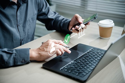 man on laptop transferring money using phone