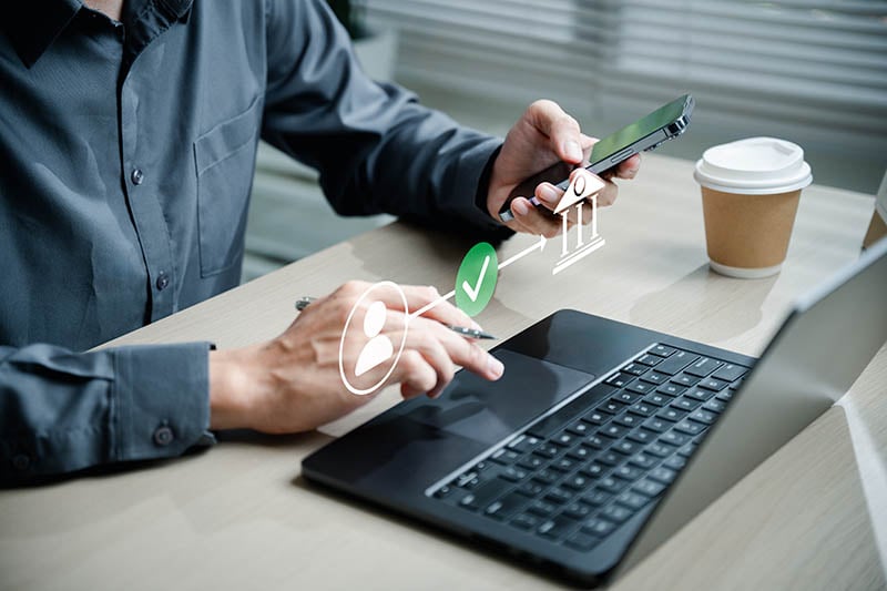 man on laptop transferring money using phone