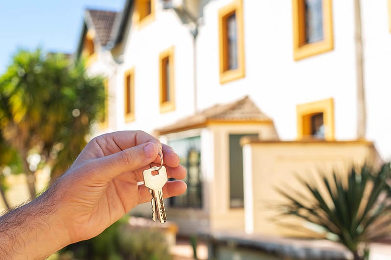 person holding keys in front of sunny property 800