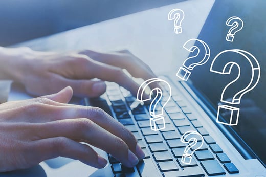 person typing on laptop with question marks