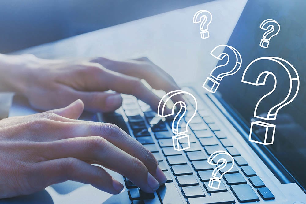 person typing on laptop with question marks