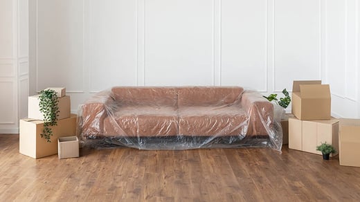sofa wrapped in plastic next to packing boxes