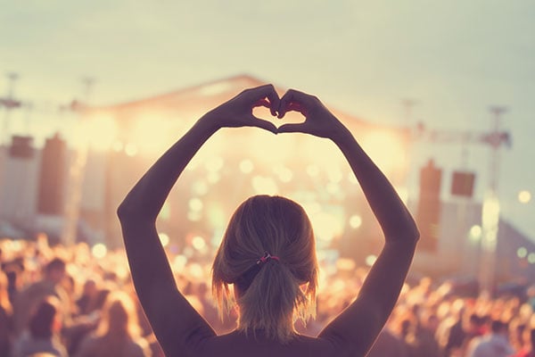 woman at festival making heart shape watching band