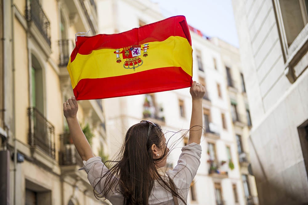 woman holding spanish flag above her head 1000