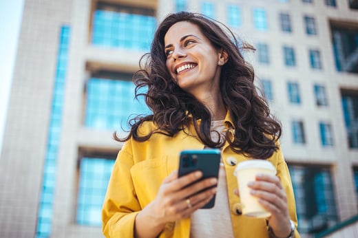 woman with a coffee and mobile phone in a yellow jacket
